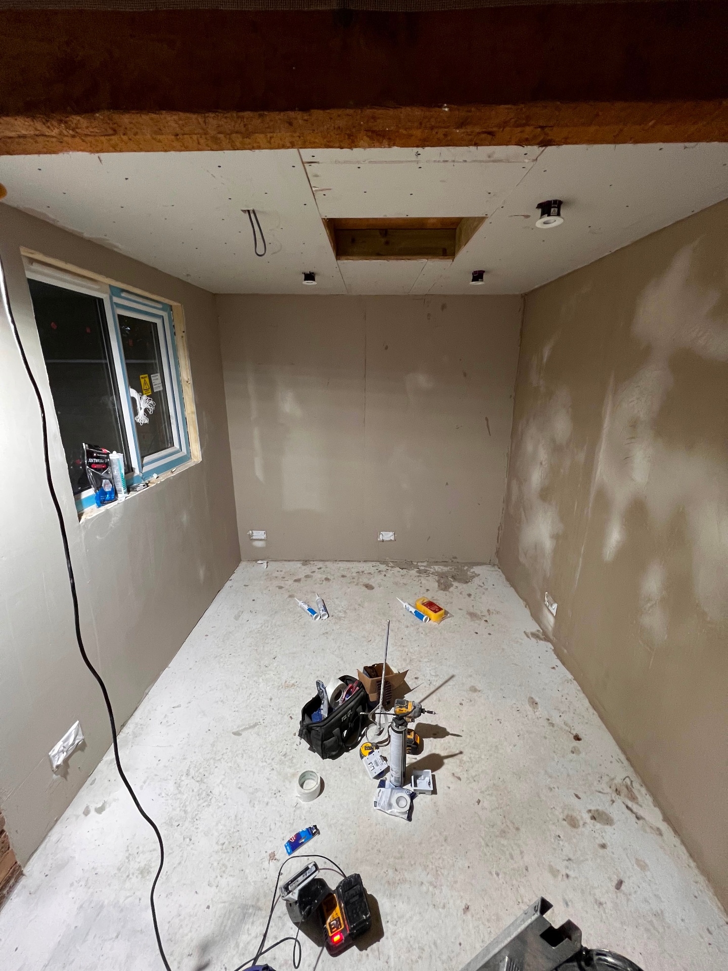 Freshly plastered room with recessed downlights and loft hatch