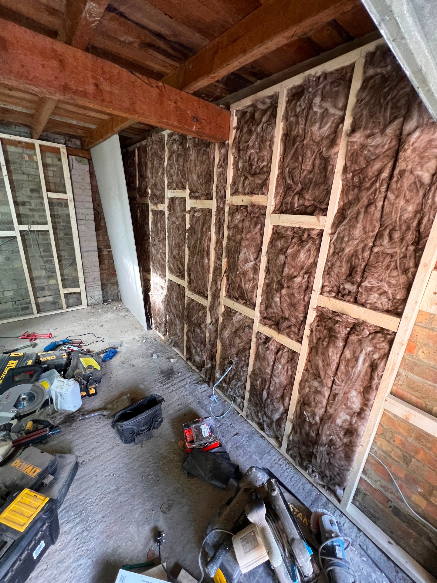 Garage conversion in progress with insulated stud walls and exposed brickwork