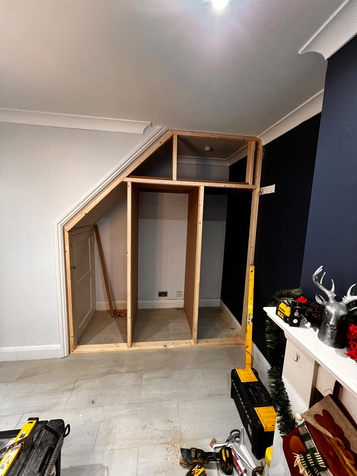 Bespoke understairs storage carcass built in situ with navy feature wall